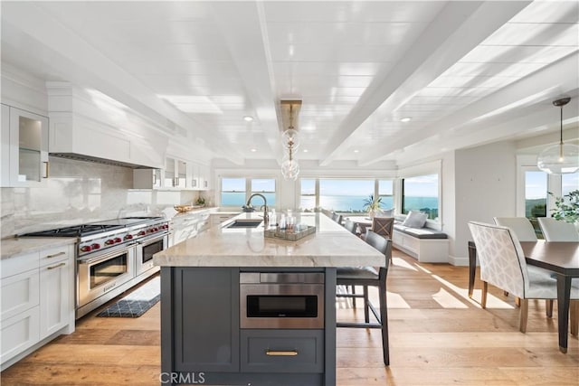 kitchen featuring white cabinets, beam ceiling, and light hardwood / wood-style flooring