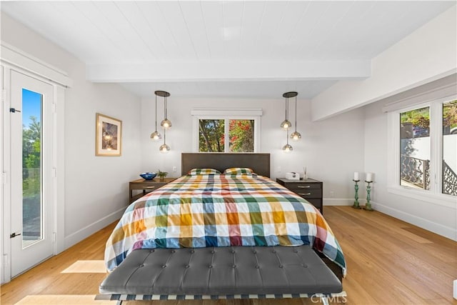 bedroom featuring beamed ceiling, light hardwood / wood-style flooring, and multiple windows