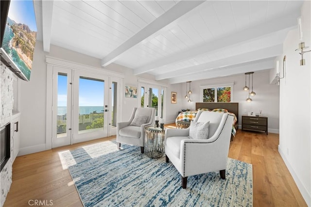 interior space featuring beam ceiling, light wood-type flooring, and a stone fireplace