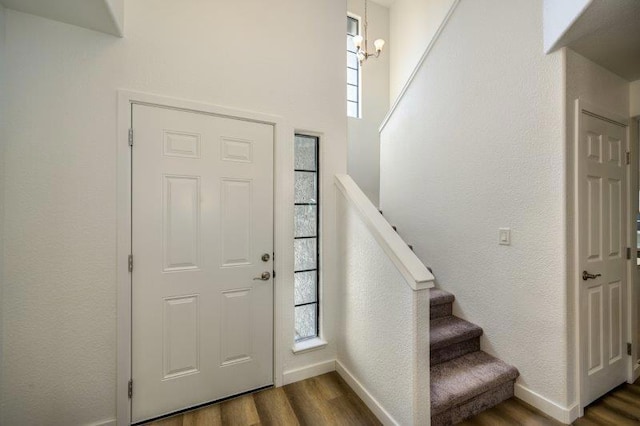 entrance foyer featuring a notable chandelier, dark wood-type flooring, and a wealth of natural light