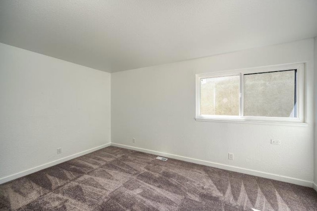 unfurnished room with dark colored carpet