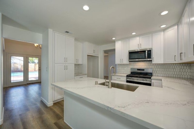 kitchen featuring stainless steel appliances, sink, white cabinetry, light stone counters, and dark hardwood / wood-style flooring