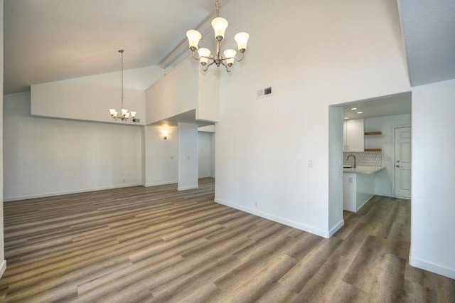 unfurnished living room with sink, a notable chandelier, high vaulted ceiling, and dark hardwood / wood-style flooring