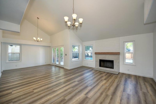 unfurnished living room with a healthy amount of sunlight, high vaulted ceiling, wood-type flooring, and a chandelier