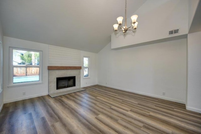 unfurnished living room with hardwood / wood-style floors, a notable chandelier, high vaulted ceiling, and a tile fireplace