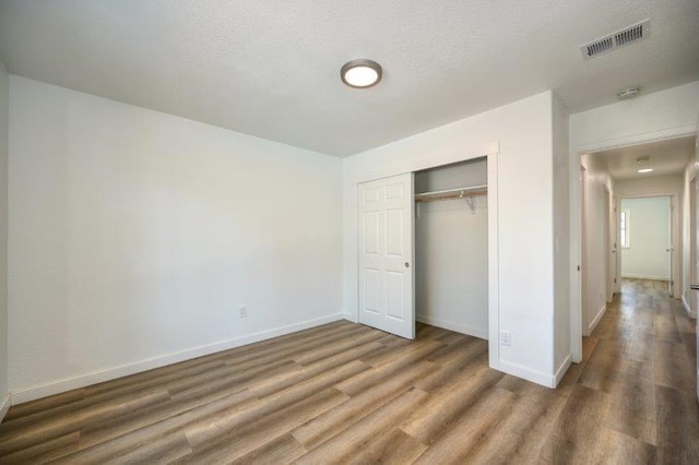 unfurnished bedroom with dark wood-type flooring, a closet, and a textured ceiling