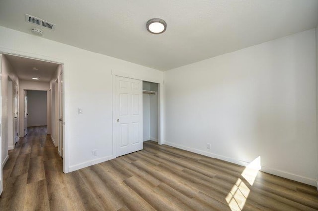 unfurnished bedroom with a closet and dark hardwood / wood-style floors