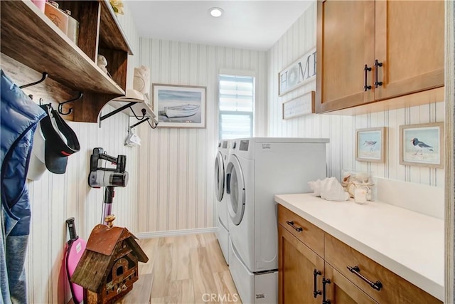 laundry room featuring cabinets, washer and dryer, and light hardwood / wood-style flooring