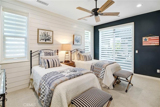 carpeted bedroom with ceiling fan and wood walls