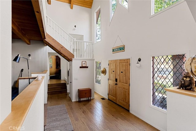 foyer with light wood-type flooring, wooden ceiling, beam ceiling, and high vaulted ceiling