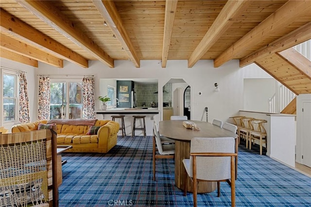 carpeted dining area featuring sink, beam ceiling, and wood ceiling