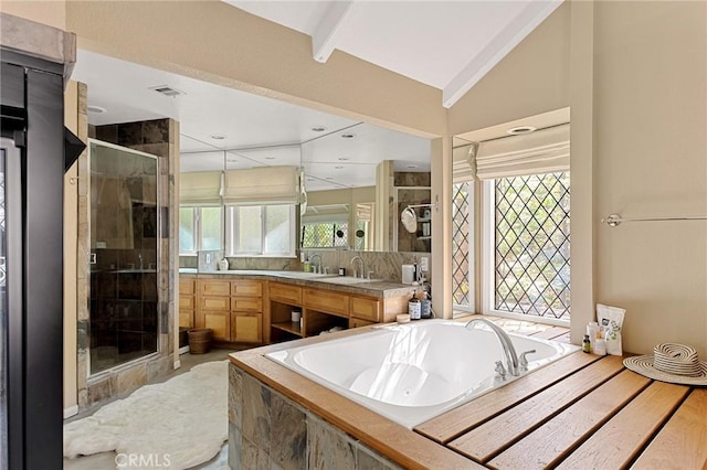 bathroom with vaulted ceiling, independent shower and bath, a wealth of natural light, and vanity