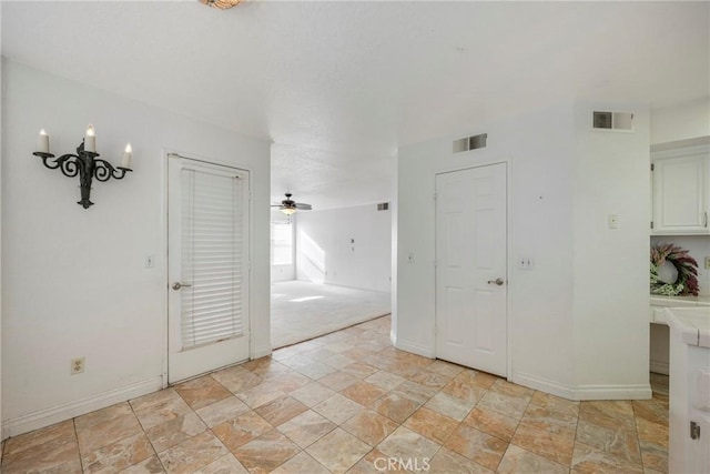 empty room with baseboards, visible vents, ceiling fan, and stone finish flooring