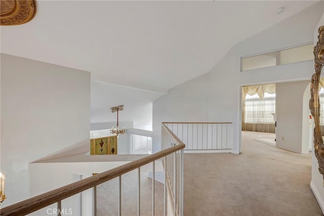 corridor featuring vaulted ceiling, carpet, and a notable chandelier