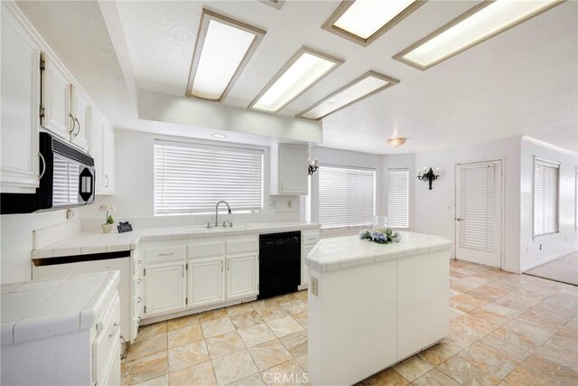 kitchen featuring a kitchen island, tile counters, white cabinets, and black appliances