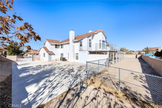 exterior space featuring a tiled roof, fence private yard, a residential view, and a chimney