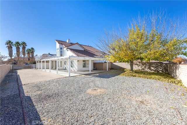 back of property featuring a tiled roof, a chimney, a patio area, and a fenced backyard