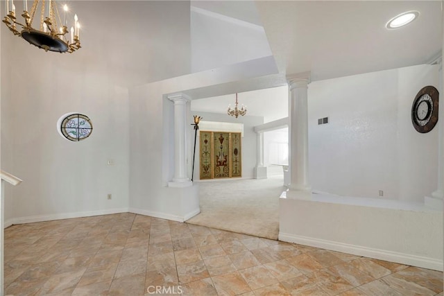 unfurnished room featuring light carpet, a notable chandelier, high vaulted ceiling, and ornate columns