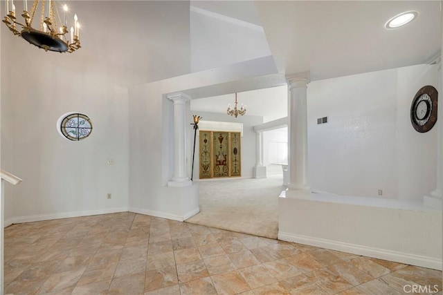 interior space featuring a chandelier, baseboards, visible vents, and ornate columns