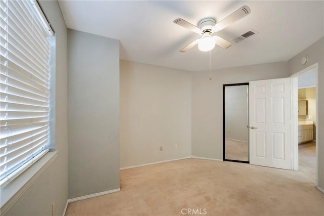 unfurnished bedroom featuring baseboards, multiple windows, visible vents, and light colored carpet