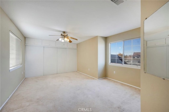 unfurnished room featuring visible vents, plenty of natural light, light carpet, and ceiling fan