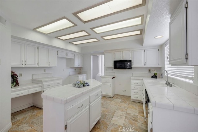 kitchen featuring tile counters, sink, a kitchen island, and white cabinets