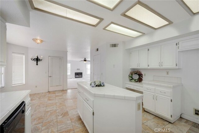 kitchen featuring a wealth of natural light, black dishwasher, a center island, and tile counters