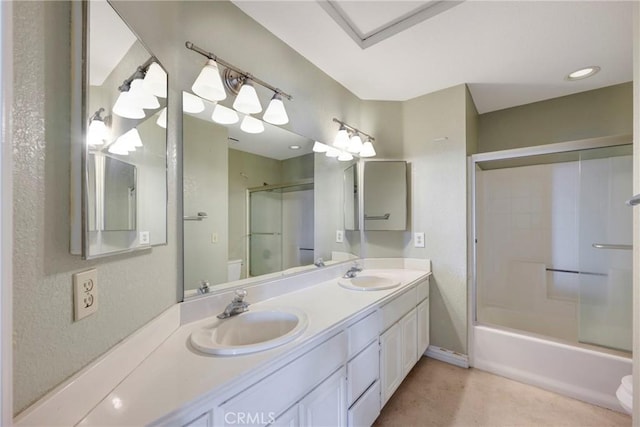 bathroom featuring double vanity, shower / bath combination with glass door, and a sink