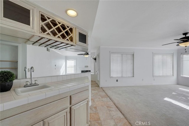 kitchen featuring tile countertops, ceiling fan, open floor plan, and a sink