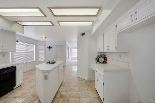 kitchen featuring a center island, tile counters, black dishwasher, and white cabinets