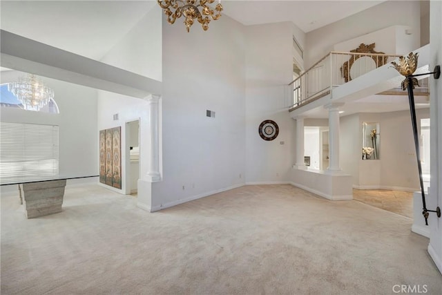 unfurnished living room featuring light carpet, a notable chandelier, and ornate columns