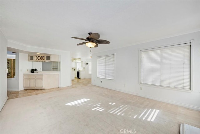 unfurnished living room with light colored carpet, crown molding, baseboards, and ceiling fan