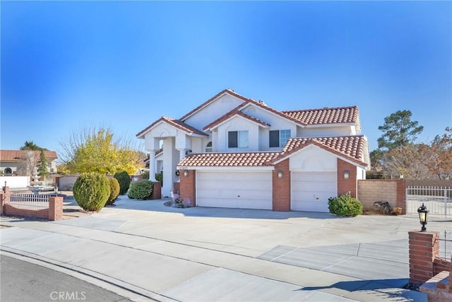 mediterranean / spanish home featuring a garage, fence, concrete driveway, and a tiled roof