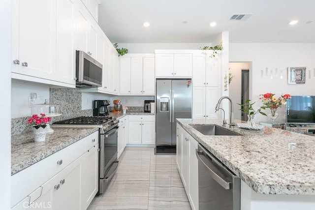 kitchen with a center island with sink, sink, white cabinetry, and stainless steel appliances