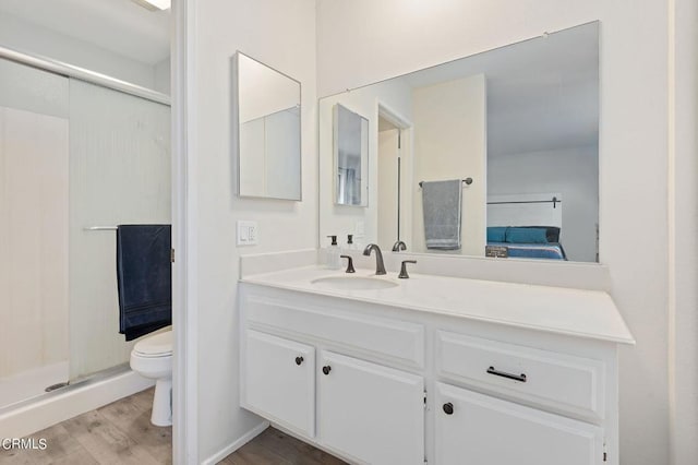 bathroom featuring a shower with door, hardwood / wood-style flooring, vanity, and toilet