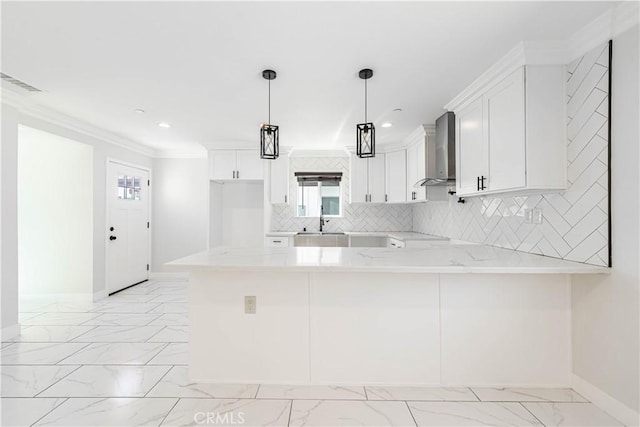 kitchen with white cabinetry, light stone countertops, wall chimney exhaust hood, kitchen peninsula, and decorative light fixtures