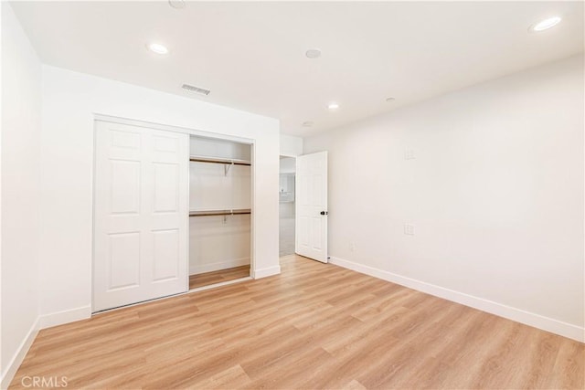 unfurnished bedroom with a closet and light hardwood / wood-style floors