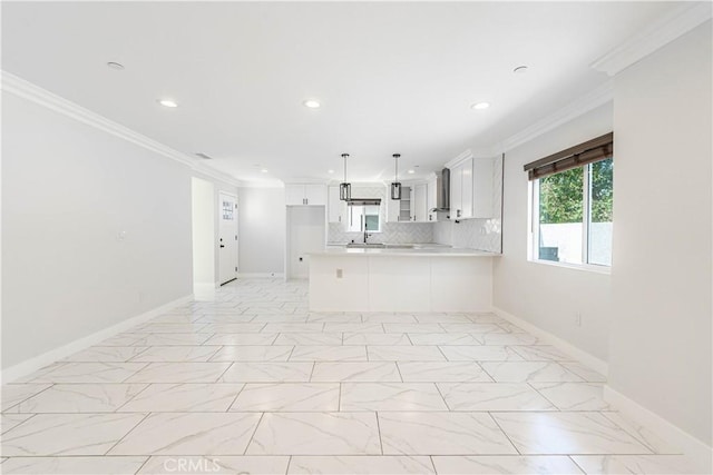 kitchen with kitchen peninsula, white cabinets, wall chimney exhaust hood, and ornamental molding