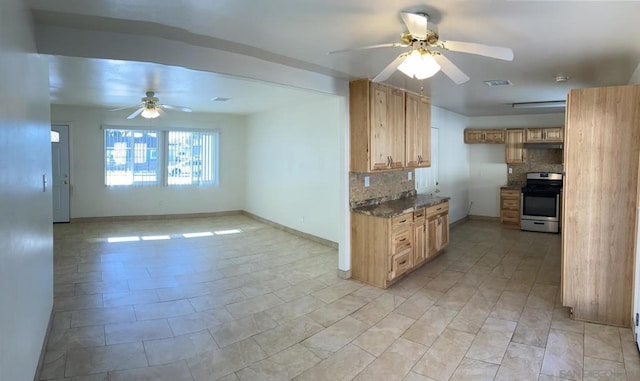 kitchen with ceiling fan, dark stone countertops, stainless steel stove, decorative backsplash, and light brown cabinets