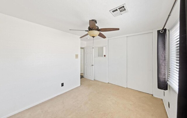 unfurnished bedroom featuring light carpet, a closet, and ceiling fan