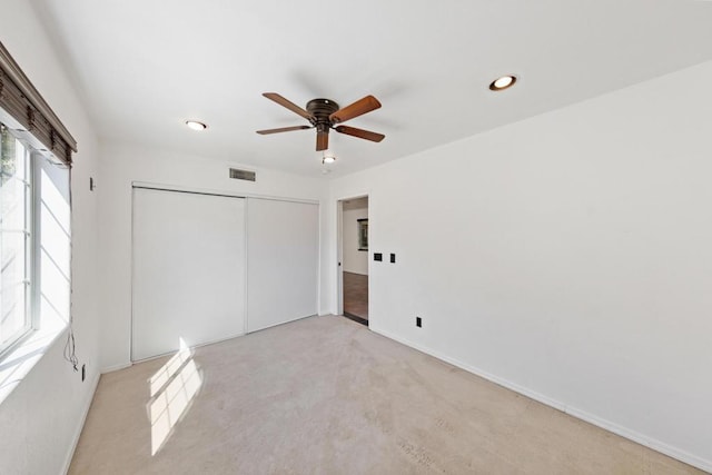 unfurnished bedroom featuring light carpet, ceiling fan, and a closet