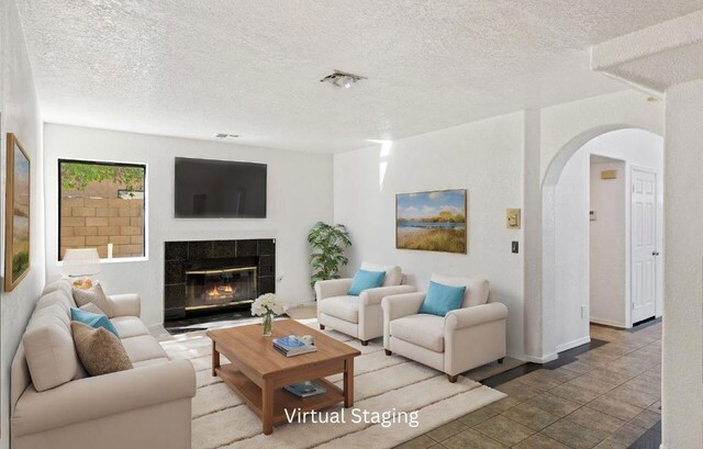 living room with a tiled fireplace and a textured ceiling