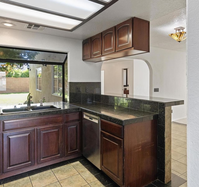 kitchen featuring dishwasher, sink, light tile patterned floors, and kitchen peninsula