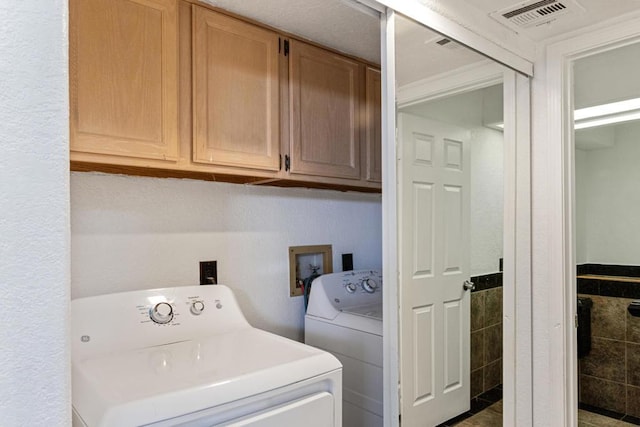 laundry room featuring cabinets, washer and dryer, and tile walls