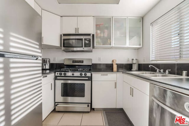 kitchen with white cabinets, appliances with stainless steel finishes, sink, and light tile patterned flooring