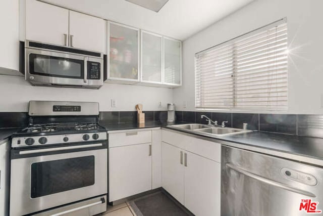 kitchen featuring light tile patterned floors, appliances with stainless steel finishes, sink, and white cabinetry