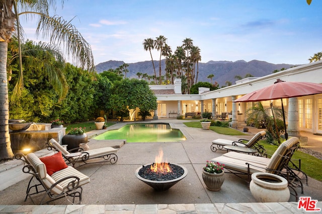 view of swimming pool featuring a mountain view, a patio, and an outdoor fire pit