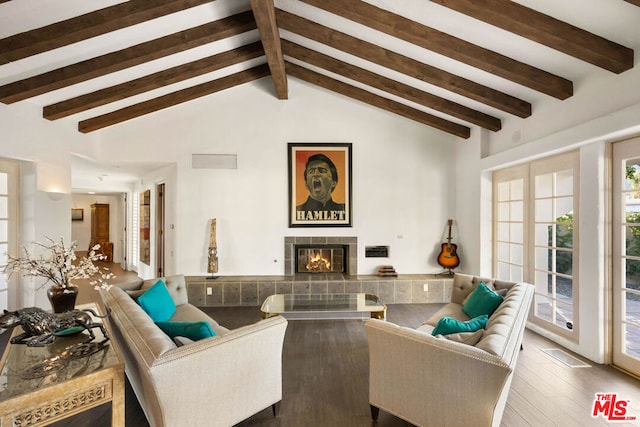 living room with a tile fireplace, hardwood / wood-style floors, and vaulted ceiling with beams