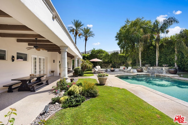 view of swimming pool featuring french doors, an outdoor fire pit, ceiling fan, a yard, and a patio