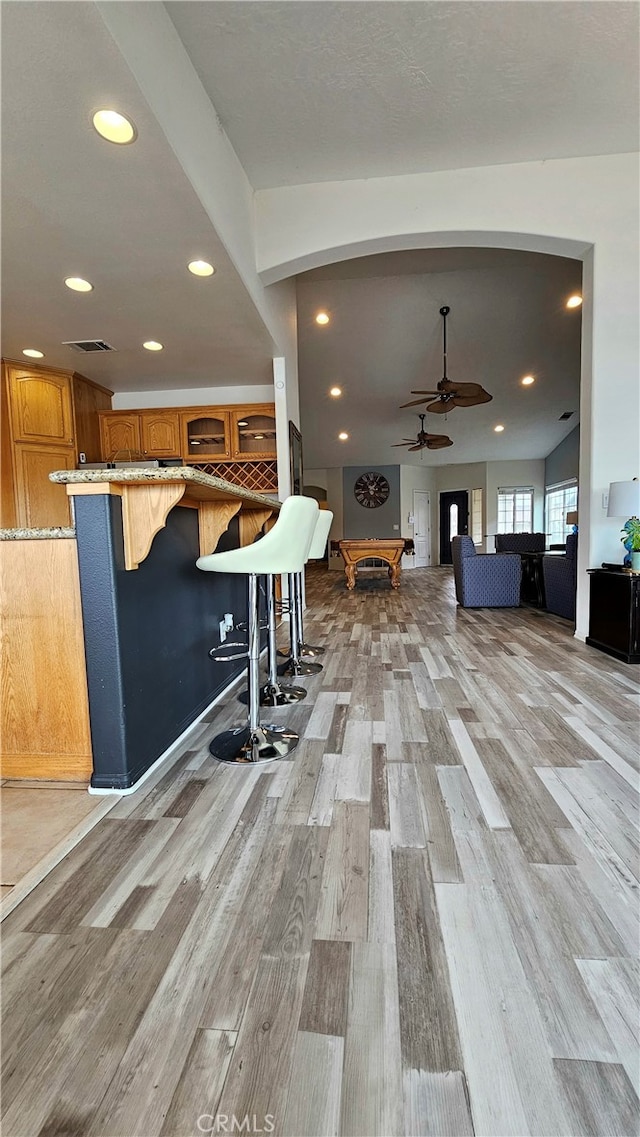 interior space featuring ceiling fan, light hardwood / wood-style flooring, a kitchen bar, and kitchen peninsula